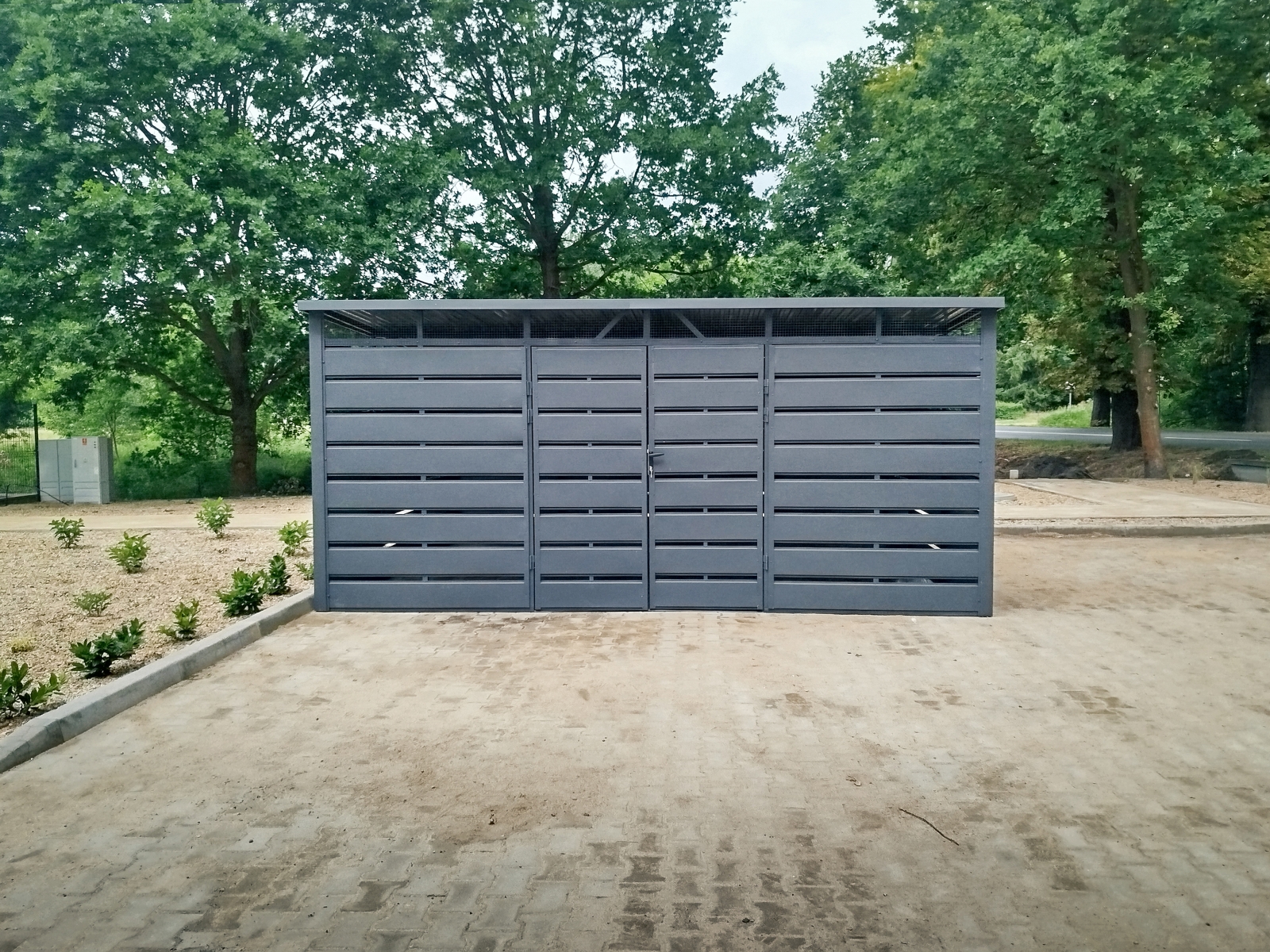 Wiata śmietnikowa o wymiarach 5x4m w panelowej zabudowie z blachy w kolorze matowy grafit z malowaną konstrukcją i niskim progiem